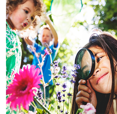 Young girl using magnifying glass to look at a flower