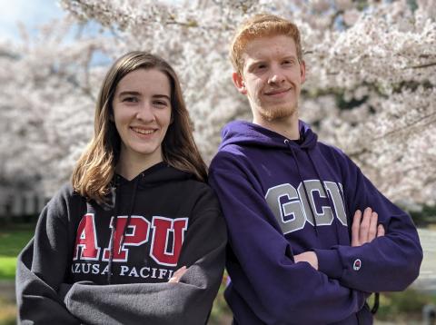 A sister and brother back to back wearing their college hoodies 
