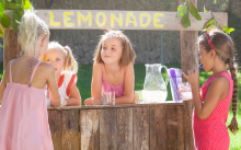 Four children buying and selling lemonade at a lemonade stand